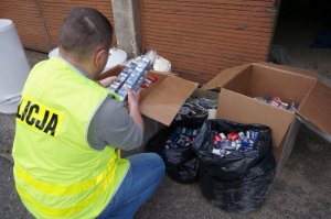 Policjant przy zabezpieczonych papierosach.