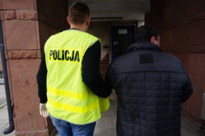 Policjant prowadzi zatrzymanego.