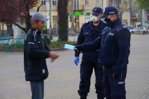 policjanci wręczają maseczkę mężczyźnie, który jej nie posiada
