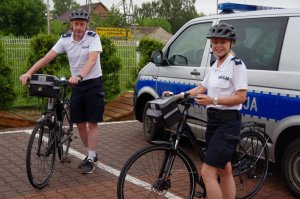 dwoje policjantów stoi przy rowerach służbowych pozując do zdjęcia