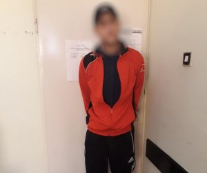 zatrzymany 24 letni mężczyzna stoi z rękami z tyłu przy drzwiach w pokoju komisariatu