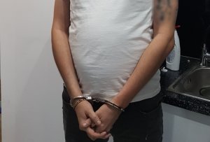 zatrzymany mężczyzna stoi przy zlewozmywaku z kajdankami założonymi na ręce trzymane z przodu