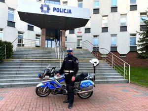 policjant młodszy aspirant Maciej Gołebiowski stoi przy służbowym motocyklu przed budynkiem Komendy Miejskiej Policji w Częstochowie
