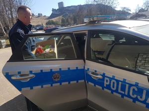 policjant stoi przy radiowozie, w tle znajduje się zamek w Olsztynie
