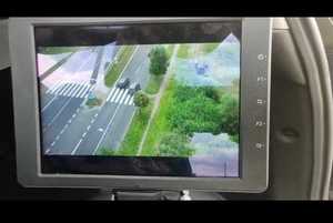zdjęcie przedstawia ekran z ujęciem stop-klatki z karmy umieszczonej na dronie, który lata na jezdnią. ujęcie przedstawia dwa pojazdy z których jeden wyprzedza drugi bezpośrednio na przejściu dla przeszych