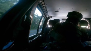 zdjęcie przedstawia wnętrze pojazdu, w którym siedzi umundurowany policjant oddziału kontrterrorystycznego patrzący w kierunku jazdy