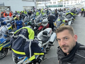 zbliżenie na twarz policjanta - w tle kilkadziesiąt motocykli policyjnych z różnych krajów