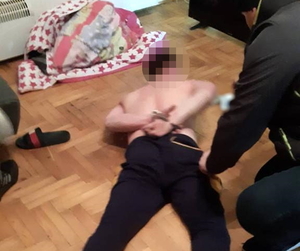na zdjęciu zatrzymany mężczyzna leży na podłodze, ma założone kajdanki na ręce, które trzyma z tyłu