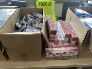 na zdjęciu zabezpieczone paczki nielegalnych papierosów w tekturowych pudełkach rozłożonych na stole