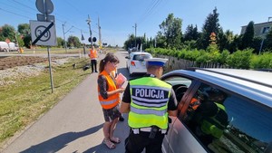 Policjanci wspólnie z pracownikami kolei rozmawiają z kierującym