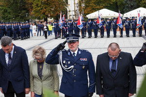 Delegacja policjanta i cywili oddaje honor przed pomnikiem