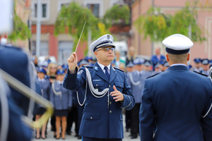 Policjant dyryguje orkiestrą w mundurach