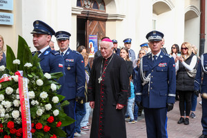 Policjanci i biskup idą z wiązanką kwiatów