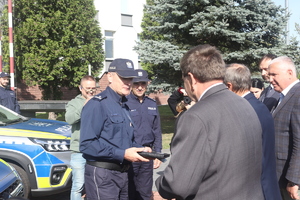 Policjant odbiera kluczyki z rąk delegacji kilku mężczyzn