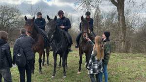 Policjanci w plenerze na koniach w towarzystwie młodzieży