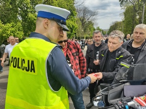 Policjant wręcza upominki uczestnikom zjazdu w tle wieża Jasnej Góry