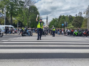 Policjant na drodze trzyma uniesiona w górę prawą rękę