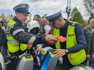 Policjanci wręczają drobne upominki uczestnikom zjazdu