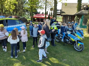 Dzieci otaczają policyjny radiowóz i motocykl w obecności policjantów