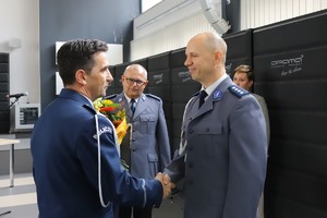 Szef częstochowskich policjantów składa gratulacje nowemu zastępcy i wręcza kwiaty, które podaje mu inny policjant