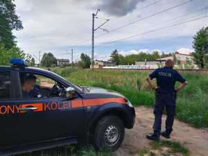 Policjant stoi przy radiowozie SOK-istów i patroluje rejon torowiska