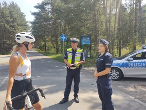 Policjanci na ścieżce rowerowej pozują do zdjęcia z rowerzystką