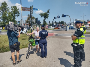 Policjanci przy drodze rozmawiają z rowerzystką