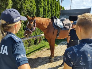 Policjantka stoi przy koniu i rozmawia z chłopcem