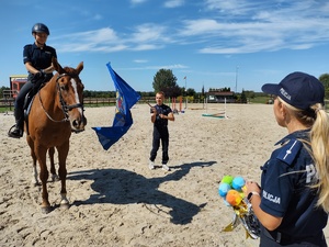 Chłopiec macha wokół konia chorągwią w obecności policjantek