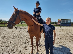 Chłopiec pozuje do zdjęcia z policjantka na koniu