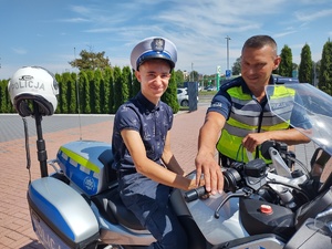 Chłopiec siedzi na policyjnym motocyklu, obok stoi policjant