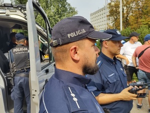 Policjanci stoją przy radiowozie podczas zabezpieczenia