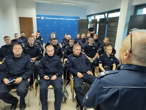 Policjanci w sali szkoleniowej słuchają tego co mówi do nich policjant