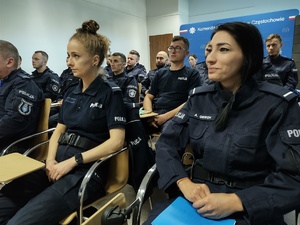 Policjanci w sali szkoleniowej siedzą na stołkach