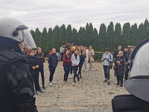 Młodzież słucha tego co mówią policjanci, którzy maja na głowach hełmy