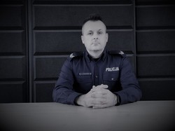 Policjant w umundurowaniu służbowym siedzi przy biurku