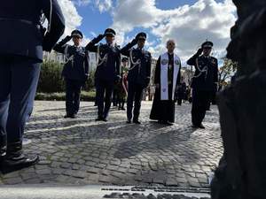 Policjanci i duchowny oddają honor przed pomnikiem