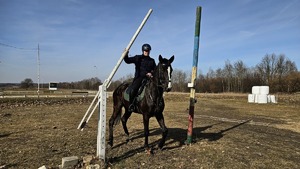 Policjant na koniu podnosi poprzeczkę