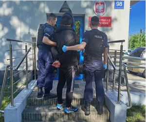 Policjanci doprowadzają zatrzymanego do komisariatu policji