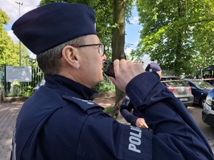 Policjant podczas zabezpieczenia mówi do stacji nasobnej