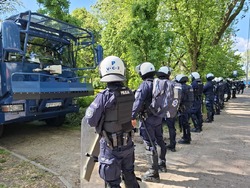 Policjanci stoją przy armatce wodnej i zabezpieczają miejsce