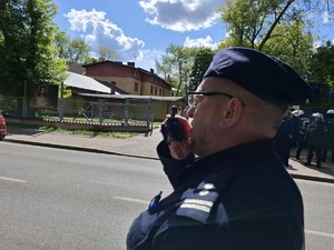 Policjant mówi do urządzenia, które trzyma w ręce