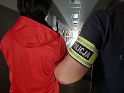 Policjant doprowadza zatrzymanego