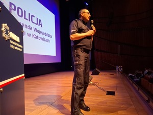 Policjant mówi do mikrofonu stojąc nascenie