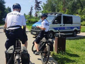 Policyjny patrol rowerowy na tle radiowozu