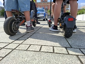 Tył hulajnóg na których znajdują się nogi chłopców