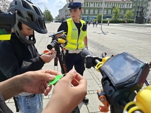 Policjantka wręcza elementy odblaskowe chłopcom