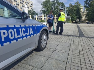 Policjanci rozmawiają z mężczyzną na hulajnodze, obok stoi radiowóz