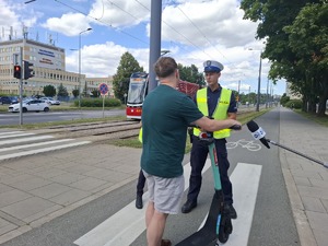 Policjanci rozmawiają z użytkownikiem hulajnogi na drodze