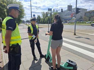 Policyjny patrol rozmawia z kobietą na hulajnodze